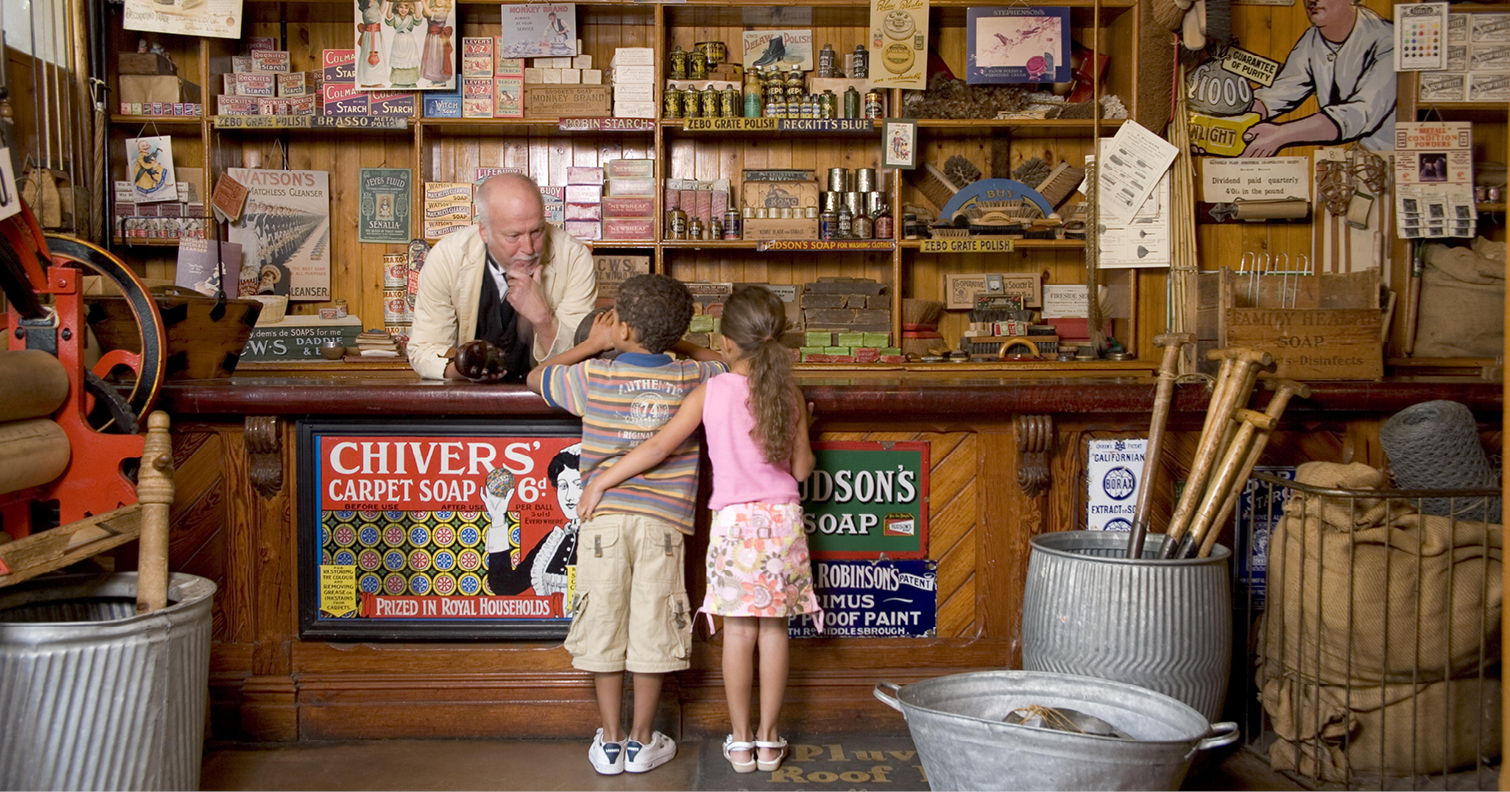 two children talking to shop keeper at 1900s town shop at Beamish Museum